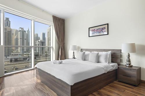 1 dormitorio con cama grande y ventana grande en VayK - Delightful 2BR in JLT with Marina Views en Dubái