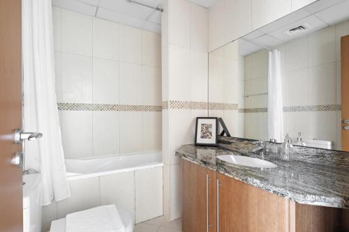 a bathroom with a sink and a tub and a toilet at VayK - Delightful 2BR in JLT with Marina Views in Dubai