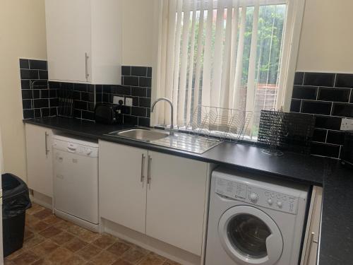 una cocina con fregadero y lavadora en Chorlton Townhouse, en Mánchester