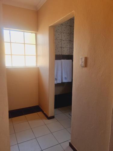 a bathroom with a window and a walk in shower at Home Life Guesthouse in Midrand