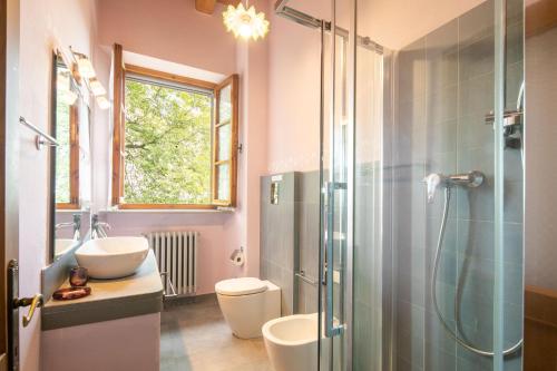een badkamer met een douche, een toilet en een wastafel bij Casale Montelucci by VacaVilla in Gaiole in Chianti
