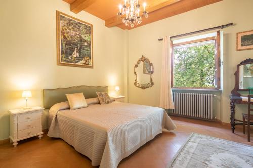 een slaapkamer met een bed, een raam en een spiegel bij Casale Montelucci by VacaVilla in Gaiole in Chianti