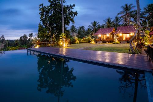 a villa with a swimming pool at night at Amanuba Ersadeva Resort in Pulukan