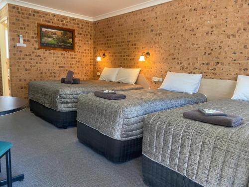 a hotel room with three beds and a brick wall at Aberdeen Motel in Aberdeen