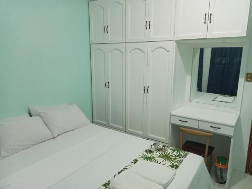een slaapkamer met een bed, een bureau en witte kasten bij Larot's Vacation House - Rooms Only in Siquijor