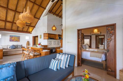 a living room with a blue couch and a bedroom at Lembongan Island Beach Villas in Nusa Lembongan
