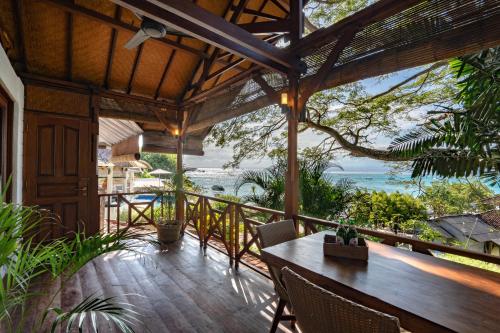 una terraza al aire libre con mesa, sillas y el océano en Lembongan Island Beach Villas en Nusa Lembongan
