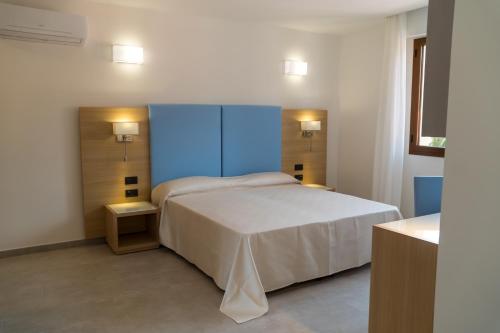 a bedroom with a white bed and a blue cabinet at Hotel Oasis in Alghero