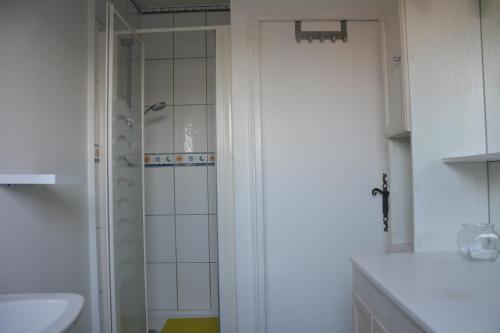 La salle de bains blanche est pourvue d'une douche et d'un lavabo. dans l'établissement La Villa Bernard, à Varennes-sur-Loire