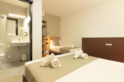a hotel room with two beds and a bathroom at Hotel La Milagrosa in Alicante