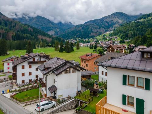 a village in the mountains with a green field at Casa Alice in Falcade