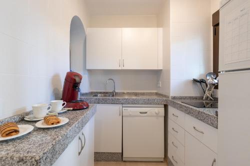 a kitchen with white cabinets and plates of food on the counter at Marina de la Duquesa 805 in Manilva
