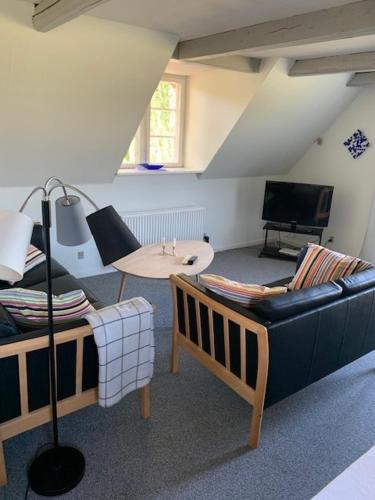 a living room with a couch and a table at Dyrlundgaard tilbyder charmerende ferielejlighed. in Helsinge