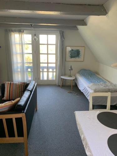 ein Wohnzimmer mit einem Sofa und einem Bett in der Unterkunft Dyrlundgaard tilbyder charmerende ferielejlighed. in Helsinge