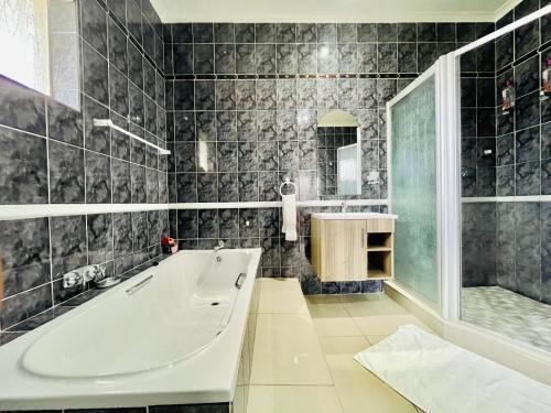 a bathroom with a tub and a shower and a sink at Entire House in Beacon Bay - Family or Group Retreat - Swimming Pool - Multiple Braais in East London