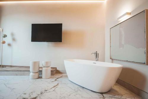 ein Bad mit einer weißen Badewanne und einem TV an der Wand in der Unterkunft Hotel City Palazzo Dei Cardinali in Rom
