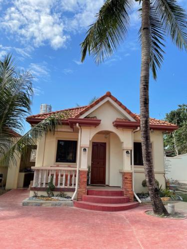 a house with a palm tree in front of it at Seaside Beach Resort in San Fabian
