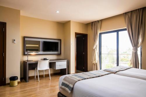 a hotel room with a bed and a desk and a television at WL Hotel Maputo City Center Mozambique Collection in Maputo