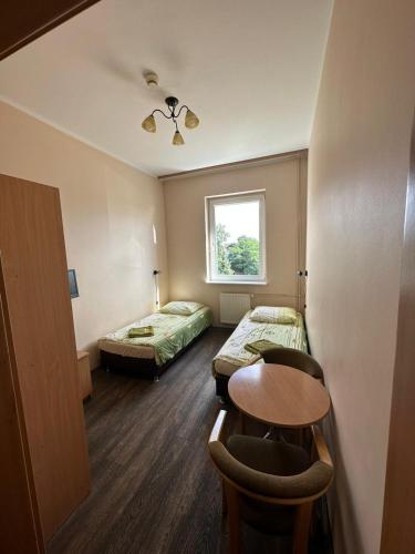 a room with two beds and a table and a window at Hostel na Fali in Gollnow