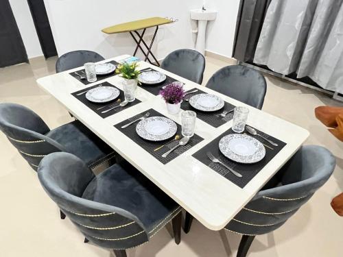 une table blanche avec des chaises autour de celle-ci, des assiettes et de la vaisselle dans l'établissement EMPIRE LUXURY HOMESTAY PAKA, à Paka