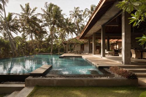 a swimming pool in front of a house with palm trees at Kirana - A Santani Villa in Bentota