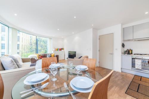 a kitchen and living room with a glass table and chairs at Family 1 Bdr Apt, Panoramic Views, Minute to Tube in London