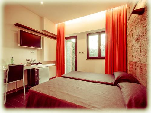 a bedroom with a bed with red curtains and a desk at All Ways Garden Hotel & Leisure in Castel di Leva