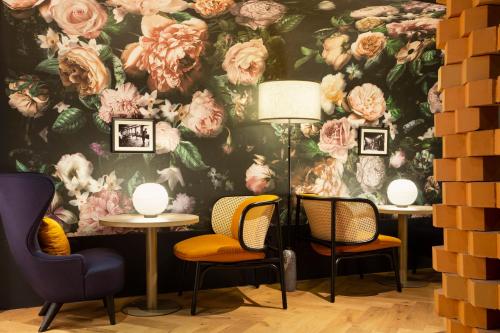 a floral wall mural in a room with chairs and tables at Hotel Les Capitouls Toulouse Centre - Handwritten Collection in Toulouse