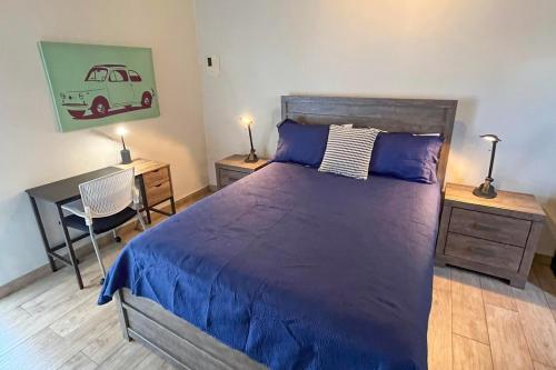 a bedroom with a large bed with a blue bedspread and a desk at The Moxy in English Harbour Town