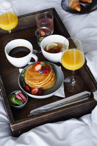 a tray with pancakes and coffee and drinks on a bed at Clarion Hotel Trondheim in Trondheim
