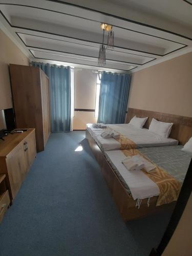 Una habitación de hotel con dos camas y un televisor. en Hotel Al Hayit Teracce, en Bukhara