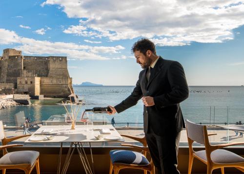 a man in a suit standing in front of a table at Hotel Royal Continental in Naples