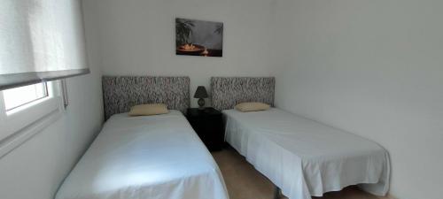 twee bedden in een kamer met witte muren en een raam bij Casa Miravent in Bellvei del Penedes
