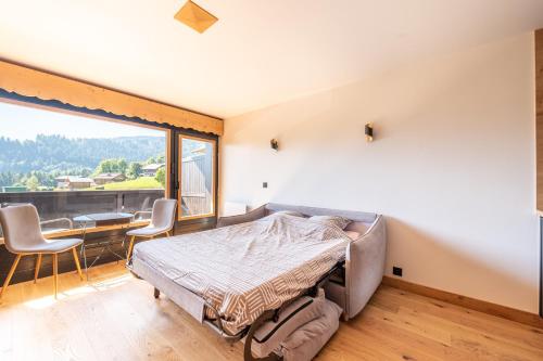 une chambre avec un lit et une grande fenêtre dans l'établissement Le Balcon du Mont Blanc - Studio refait à neuf, à Cordon