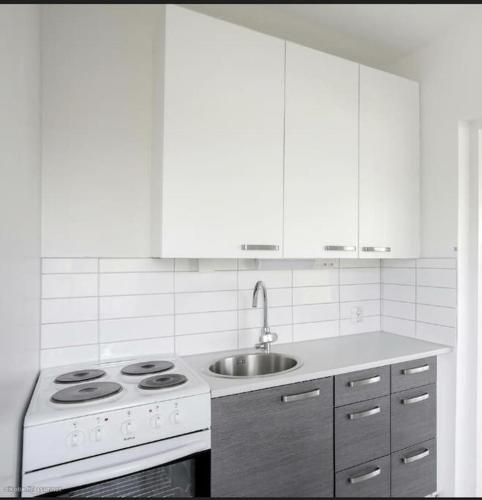 a white kitchen with a stove and a sink at Kaupunkikoti erinomaisella sijainnilla in Porvoo