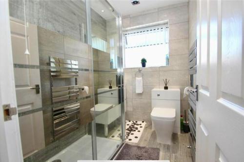 baño con aseo y lavabo y ventana en Full Modern Home - short & long stays, 
