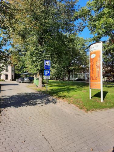 two signs on a sidewalk next to a park at Hotel Pils with Self-Check in in Sigulda