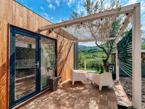 a patio with a table and chairs and a glass door at Elysian Fields - Tiny House 'Evergreen' in Sadu