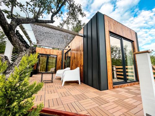 a house with a black exterior and a white chair on a deck at Elysian Fields - Tiny House 'Evergreen' in Sadu