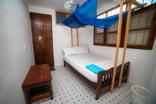 a small bedroom with a bed and a table at Flamingo Guest House ZNZ in Stone Town