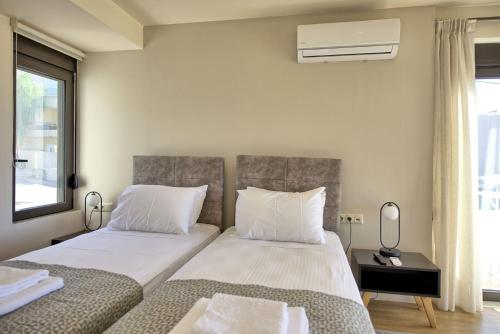 a bedroom with two beds and a window at Phaedra by PosarelliVillas in Kounoupidhianá