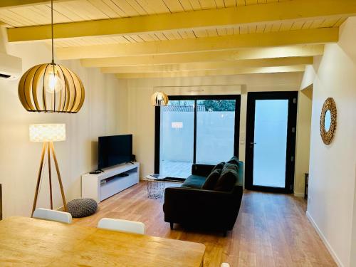 ein Wohnzimmer mit einem schwarzen Sofa und einem TV in der Unterkunft La Halte Occitane - Logement neuf 6 personnes 3 chambres tout confort in Montauban