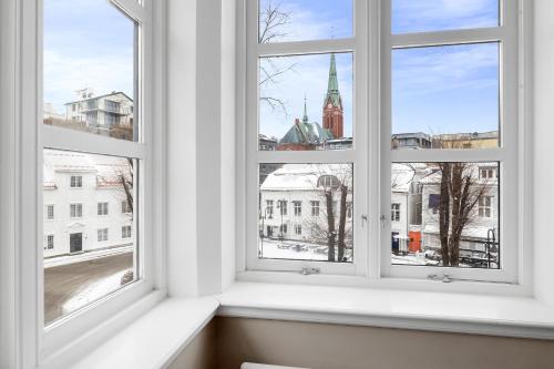 a room with three windows with a view of a city at Clarion Hotel Tyholmen in Arendal