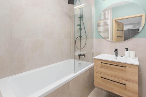 a bathroom with a tub and a sink and a mirror at Enjoy! Ursus in Warsaw