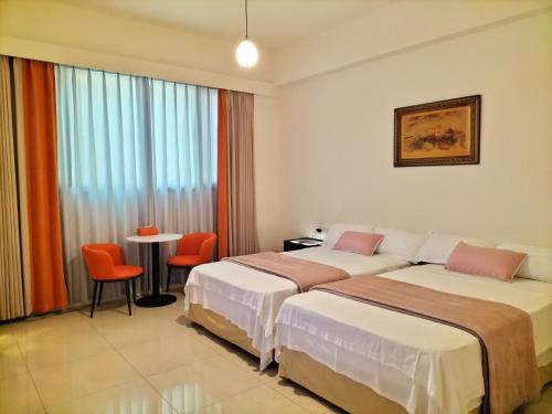 two beds in a hotel room with a table and chairs at Jing Cheng Homestay in Jincheng