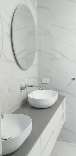 Baño blanco con lavabo y espejo en Apartment Twelve, en Taupo