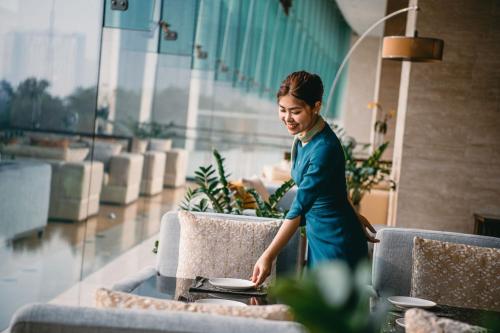 a woman in a blue dress standing next to a table at JW Marriott Hotel Hanoi in Hanoi