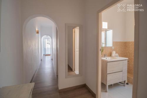 a hallway with a white bathroom with a sink and a mirror at Villa Fonte in Port de Pollensa