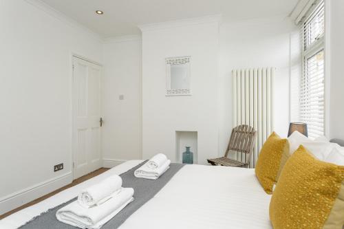 una camera da letto bianca con un letto e asciugamani di Percy Terrace - Charming 2 bedroom town house a Portsmouth