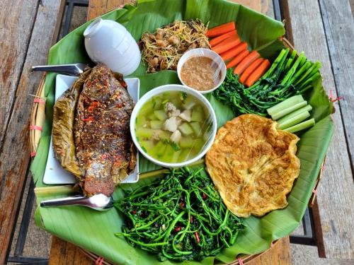 a plate of food with meat and vegetables on a banana leaf at The Mae Homstayผาฮี้ in Ban Ko Doi Tung